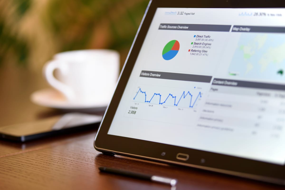 A tablet displaying campaign performance analytics, including traffic sources and visitor trends.